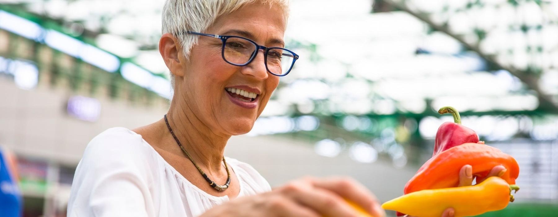 a woman smiling and holding a bunch of vegetables