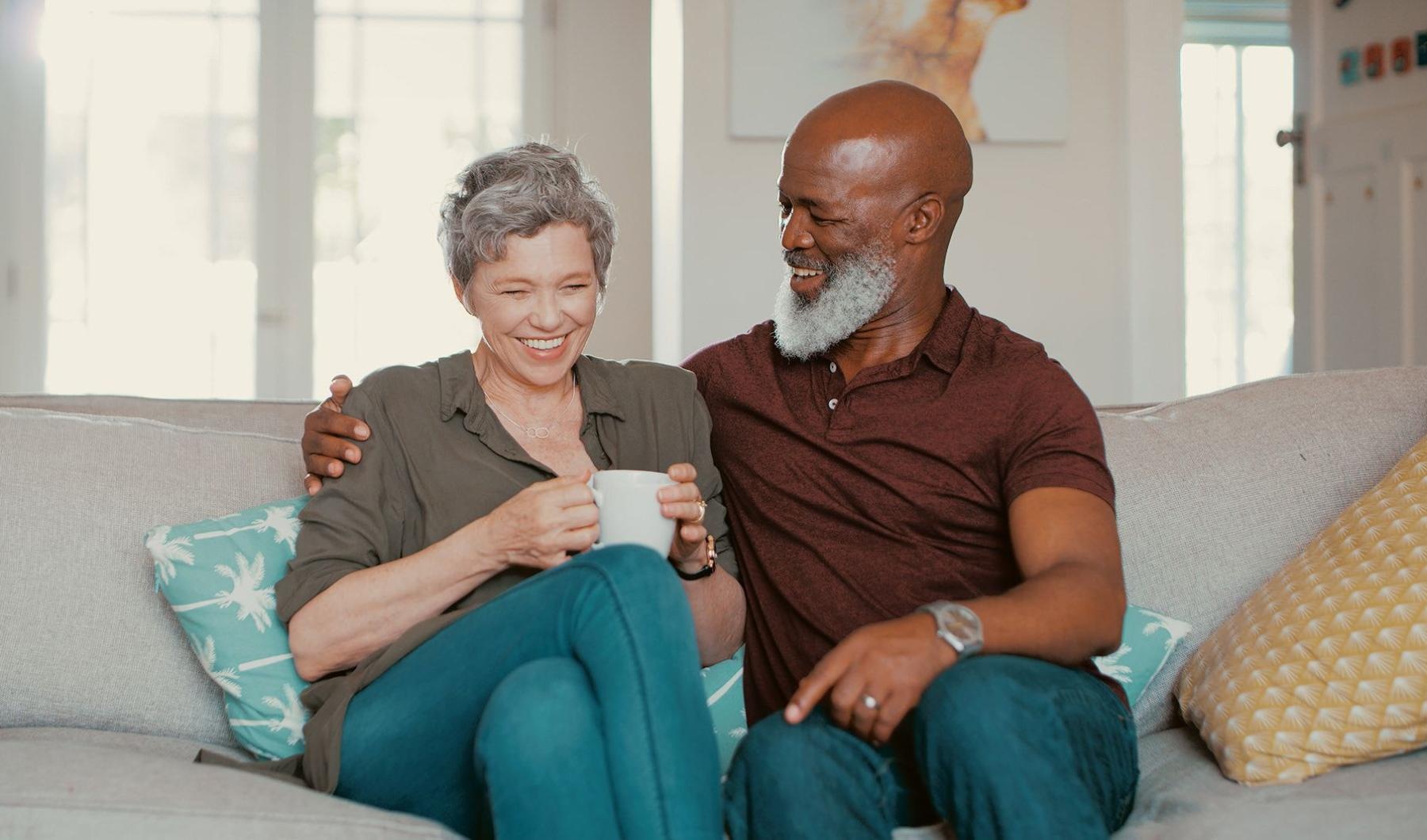 Settle into comfort at The Preserve at Gateway smiling, older couple, sit together on a couch